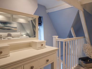 A bedroom with a dresser and a mirror at The Nutshell in Aldeburgh