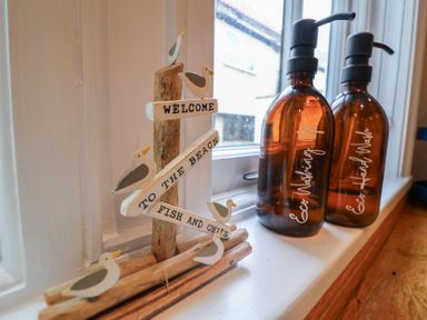 A kitchen countertop with a decorative sign and hand wash dispensers at The Nutshell in Aldeburgh