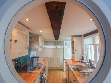 A kitchen with a stove and sink at The Nutshell in Aldeburgh