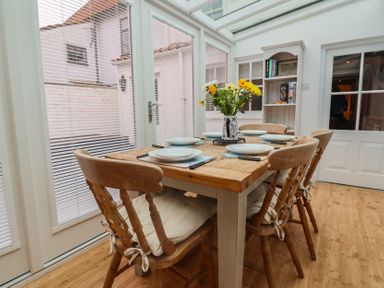 A conservatory with a table and chairs at The Nutshell in Aldeburgh