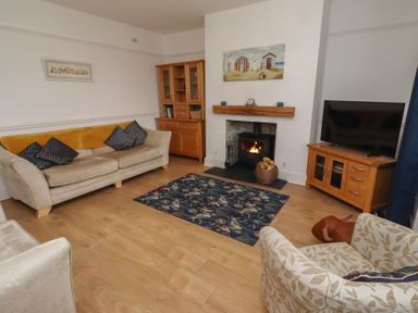 A living room with a sofa, armchair, and fireplace at 23 Northumbria Terrace Amble