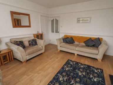 A living room with sofas and a rug at 23 Northumbria Terrace Amble