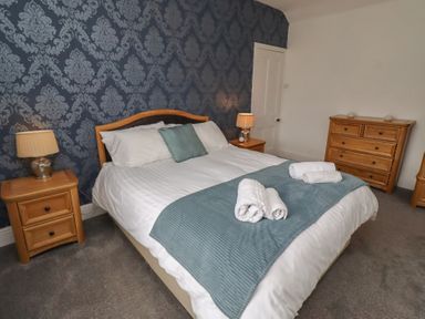 A bedroom with a bed and bedside tables at 23 Northumbria Terrace Amble