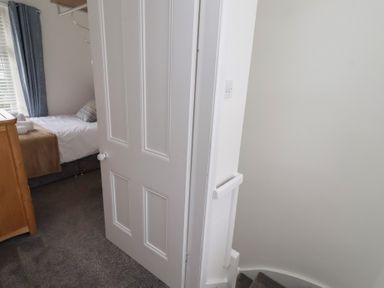 A bedroom with a bed and door at 23 Northumbria Terrace Amble