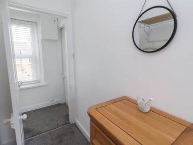 A hallway with a mirror and a wooden drawer at 23 Northumbria Terrace in Amble