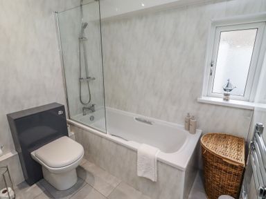 A bathroom with a bathtub and shower at 23 Northumbria Terrace in Amble
