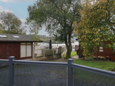 An outdoor view of boats at a dock with trees and buildings at 7 Lake View in Windermere
