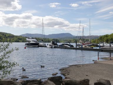A view of boats at a dock on a lake with mountains in the background at 7 Lake View in Windermere