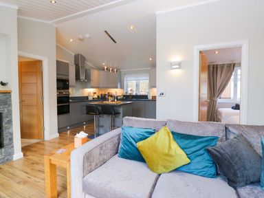 A living room with a sofa and kitchen area at 7 Lake View, Lake View 7, White Cross Bay near Windermere