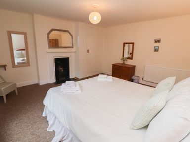 A bedroom with a bed and a mirror at Duke Cottage in Woodbridge
