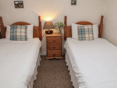 A bedroom with twin beds and a bedside table at Duke Cottage in Woodbridge