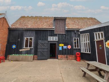 A building with a mud kitchen sign and tables at Duke Cottage in Woodbridge