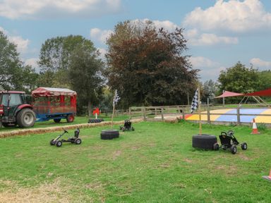 An outdoor play area with go-karts and a tractor at Duke Cottage in Woodbridge