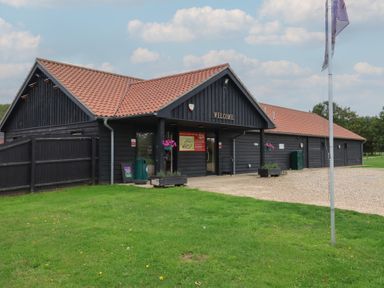A building with a welcome sign and flowers at Duke Cottage in Woodbridge