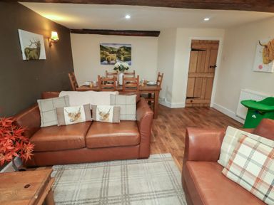 A living room with a sofa and dining area at Duchess Cottage in Woodbridge