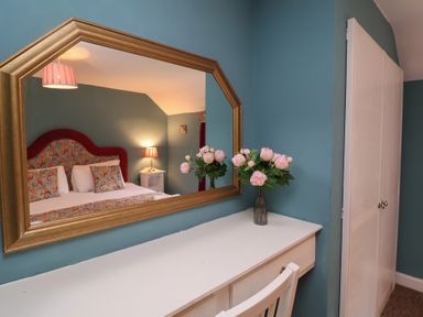 A bedroom with a mirror and bed at Duchess Cottage in Woodbridge