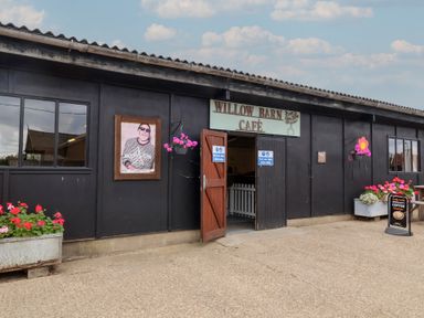 Exterior view of a café with flowers and a sign at Willow Barn Café in Woodbridge