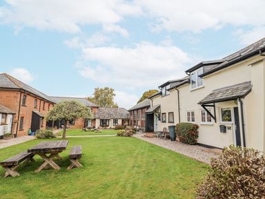 An outdoor area with buildings and a picnic bench at Rushmoor Cottage in Colaton Raleigh
