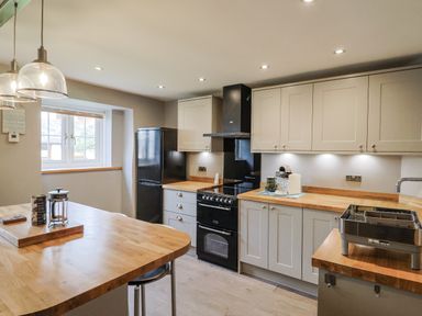 A kitchen with a refrigerator, stove, and countertop at Rushmoor Cottage in Colaton Raleigh