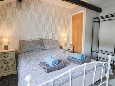 A bedroom with a bed and bedside table at Rushmoor Cottage in Colaton Raleigh