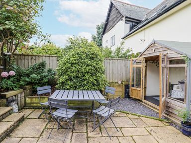 A garden with a table and chairs by a shed at Rushmoor Cottage in Colaton Raleigh