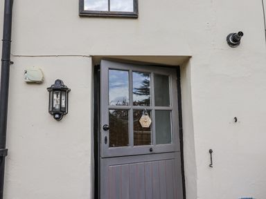 An exterior view of a gray door and light fixture at Rushmoor Cottage Colaton Raleigh