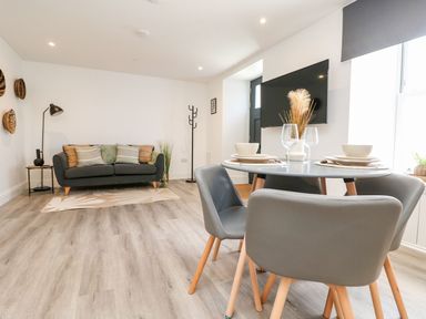 A living room with a sofa and dining area at Klysa in Camborne