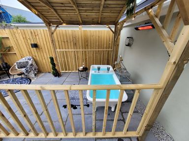 An outdoor area with a bathtub, chair, and table at Klysa in Camborne