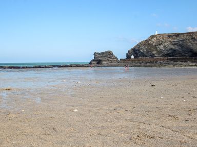 A beach scene with rocks and people wading at Klysa in Camborne