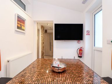 A dining room with a table and television at Teylu in Camborne
