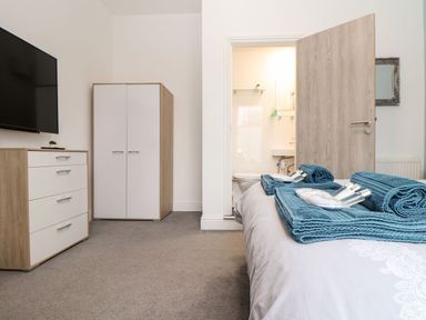 A bedroom with a television, chest of drawers, and towels at Teylu in Camborne