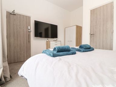 A bedroom with towels on the bed and a television mounted on the wall at Teylu Camborne