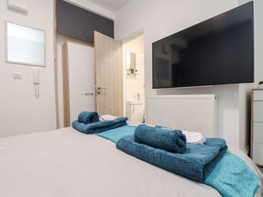 A bedroom with towels on the bed and a television on the wall at Teylu, Camborne