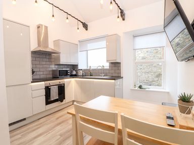 A kitchen with appliances and dining table at Battell Chambers Camborne