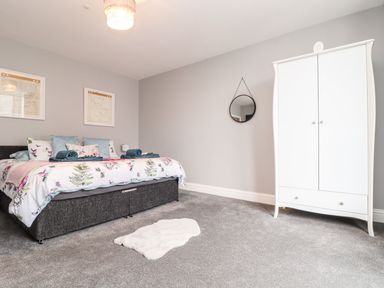 A bedroom with a bed, wardrobe, and wall art at Battell Chambers in Camborne