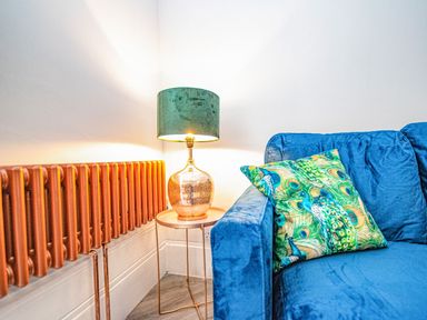 A living room with a blue sofa and a table lamp at Mews Retreat in Camborne