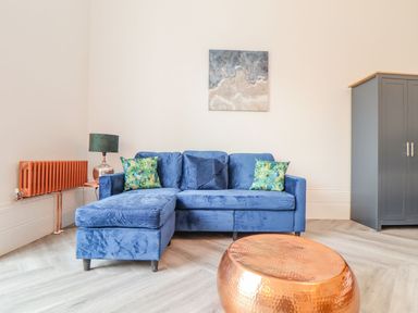A living room with a blue sofa and wall art at Mews Retreat in Camborne