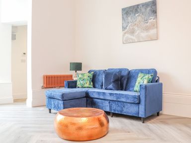 A living room with a blue sofa and copper coffee table at Mews Retreat in Camborne