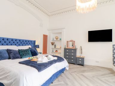 A bedroom with a blue bed, TV, and decorative items at Mews Retreat in Camborne