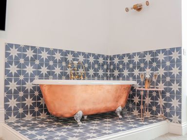 A bathroom with a copper bathtub and patterned tiles at Mews Retreat in Camborne