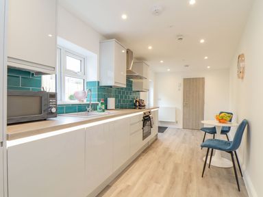 A kitchen with a microwave, sink, and table at Mews Retreat in Camborne
