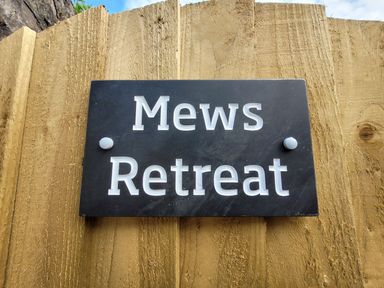 A sign for Mews Retreat on a wooden fence at Mews Retreat in Camborne