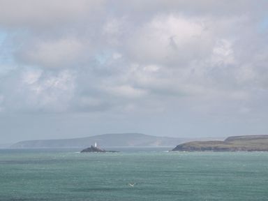A view of the ocean and a lighthouse on an island at Mews Retreat in Camborne