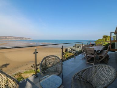 An outside area with seating and a view of the beach at Gilfach Goed in Abersoch