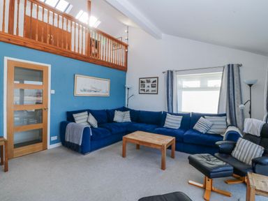 A living room with a blue sofa and wooden coffee table at Gilfach Goed in Abersoch