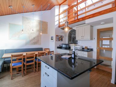 A kitchen with a table, chairs, and a map at Gilfach Goed in Abersoch