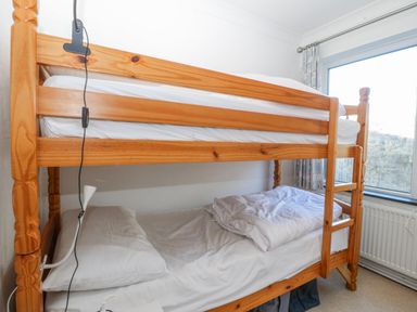 A bunk bed with linens and a window at Gilfach Goed in Abersoch