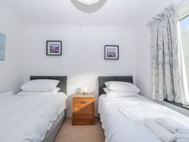 A bedroom with twin beds and bedside table at Gilfach Goed in Abersoch