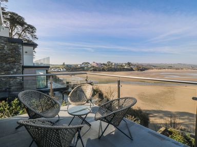 A balcony with chairs and a table overlooking the beach at Gilfach Goed in Abersoch
