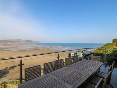 An outdoor terrace with a table and chairs overlooking the sea at Gilfach Goed in Abersoch